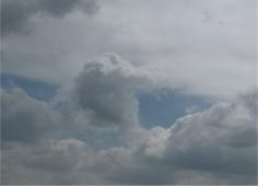 Image en format portrait avec des nuages gris sur fond de ciel bleu
