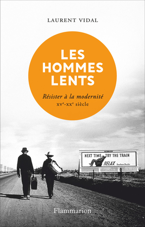 Couv Les hommes lents Couverture de l'ouvrage Les hommes lents, montrant deux hommes marchant sur une route devant une pancarte vantant le rail