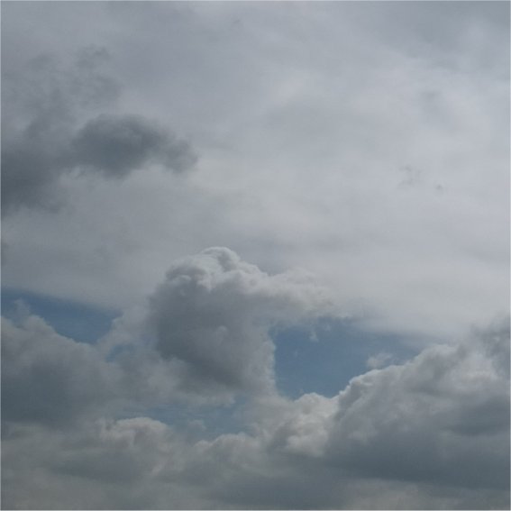 Image en format portrait avec des nuages gris sur fond de ciel bleu