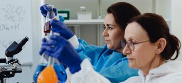 deux femmes qui ont des Erlenmeyers contenant des liquides colorés dans les mains