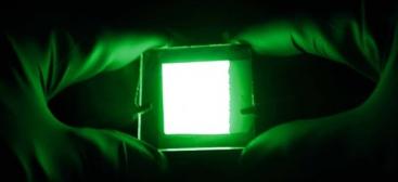 two gloved hands holding and LED green light