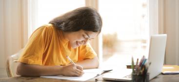 femme en tshirt jaune écrivant à son bureau