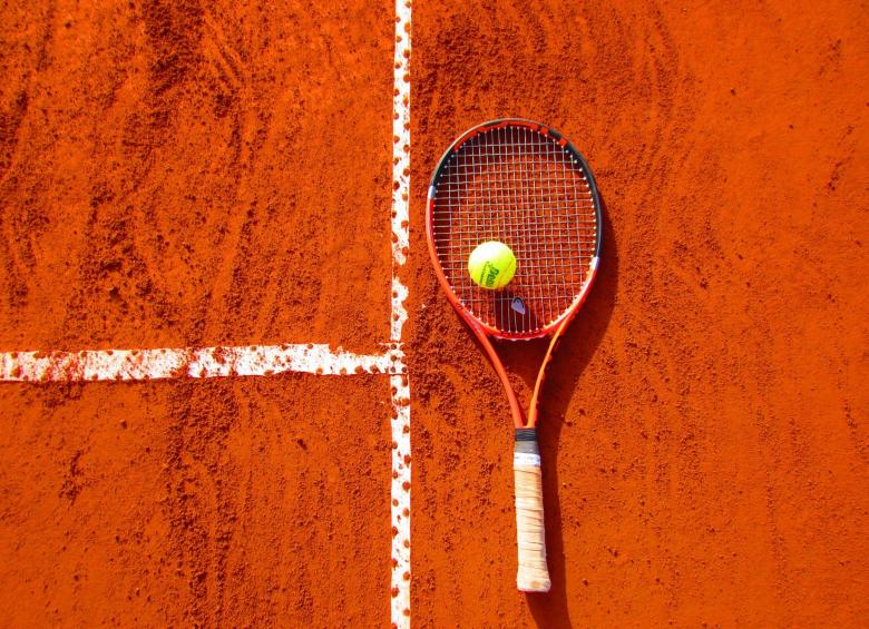 Raquette et balle de tennis posées sur un terrain terre battue