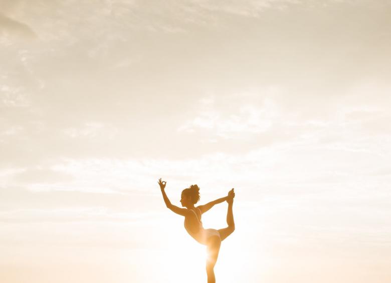 Une femme s'exerçant au Yoga devant le soleil