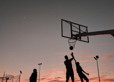 Joueurs de basketball marquant un panier devant un coucher de soleil