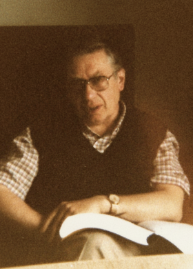 Photo de Jacques Chaurand assis avec un livre sur les genoux